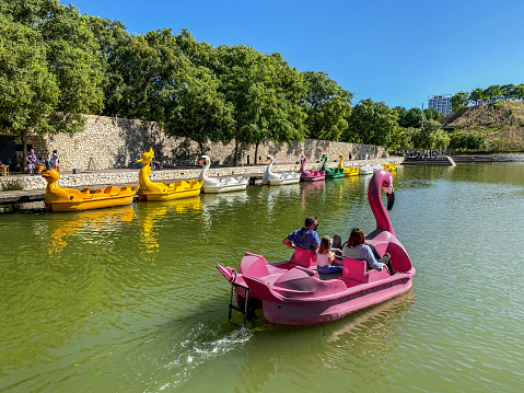 Valencia, Spain - September 27, 2020: A couple with a child riding pedal boat during the COVID-19 pandemic. Despite being outdoors people was encouraged to use a mask at all times to protect themselves an others