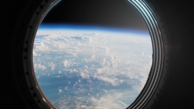 The surface of the Earth is visible in the porthole of the spacecraft
