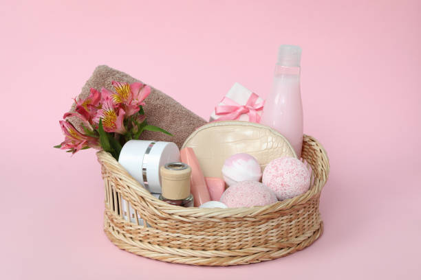 Wicker basket with cosmetics on pink background