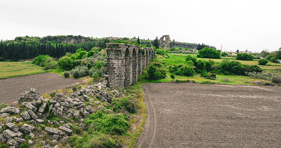 The Aspendos aqueduct has a special feature that is rare in Turkey: The printing towers necessary for the water supply of the Acropolis. The water brought from the Taurus Mountains at a distance of about 20 km had to be transported from the plain in front of the Acropolis Mountain near today's village Bekis to the Nymphaeum in the Acropolis. Printing towers were erected on both sides of the plain and connected to each other by means of a stone pressure pipe.\nThe free-flowing water coming from the mountains was collected in a basin in the pressure tower near today's village Sarıabalı and pressed to the required height in the southern tower by the dead weight of the water (a water pressure of 4.5 bar was calculated).\nAn earthquake in 363 AD destroyed large parts of the aqueduct. The further use of the perforated bricks of the pressure pipeline during the construction of the bridge over the Eurymedon shows that the aqueduct was no longer in operation from this time.