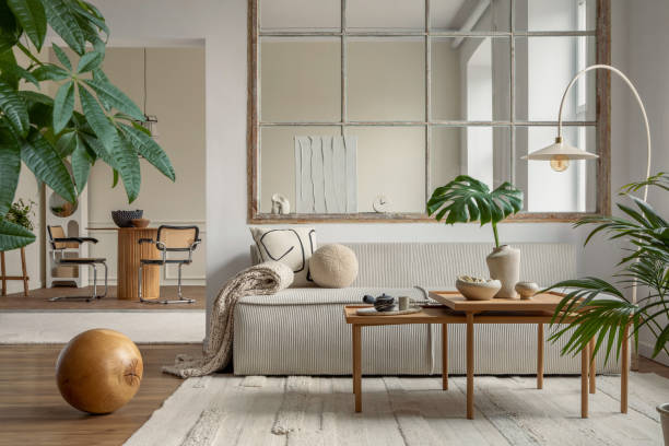 istock Open space interior with modular sofa, wooden coffee table, big window, beige rug, braided plaid, pillows, round table, lamp, plants, slippers, ball and personal accessories. Home decor. Template. 1495354598