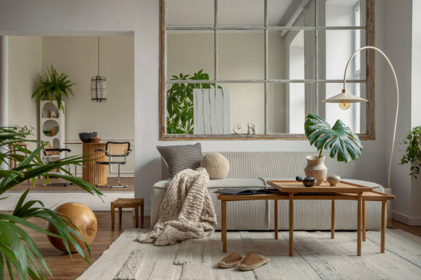 istock Open space interior with modular sofa, wooden coffee table, big window, beige rug, braided plaid, pillows, round table, lamp, plants, slippers, ball and personal accessories. Home decor. Template. 1495354665