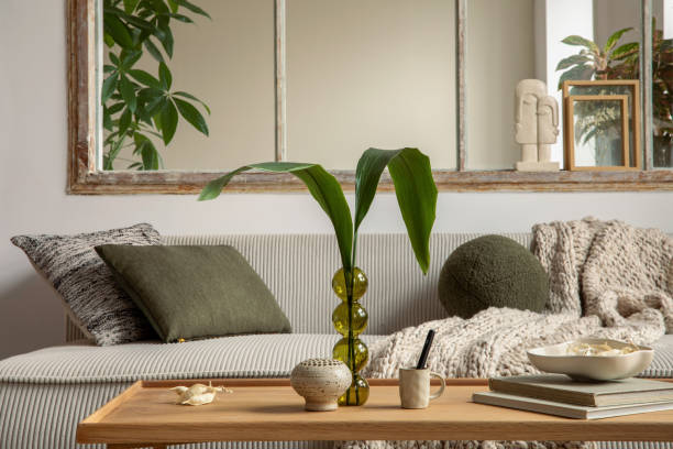 istock Aesthetics composition of open space interior with modular sofa, wooden coffee table, cup window, braided plaid, books, bowl, glass vase with leaves and personal accessories. Home decor. Template. 1495354723