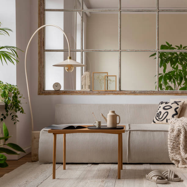 istock Interior design of open space interior with modular sofa, big window, stylish lamp, wooden coffee table, round table, rattan chair, pillows, plants and personal accessories. Home decor. Template. 1495354749