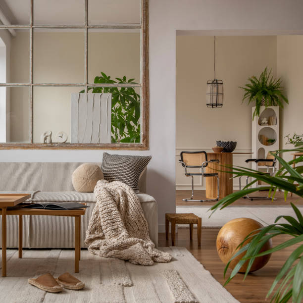 istock Open space interior with modular sofa, wooden coffee table, big window, beige rug, braided plaid, pillows, round table, lamp, plants, slippers, ball and personal accessories. Home decor. Template. 1495354765