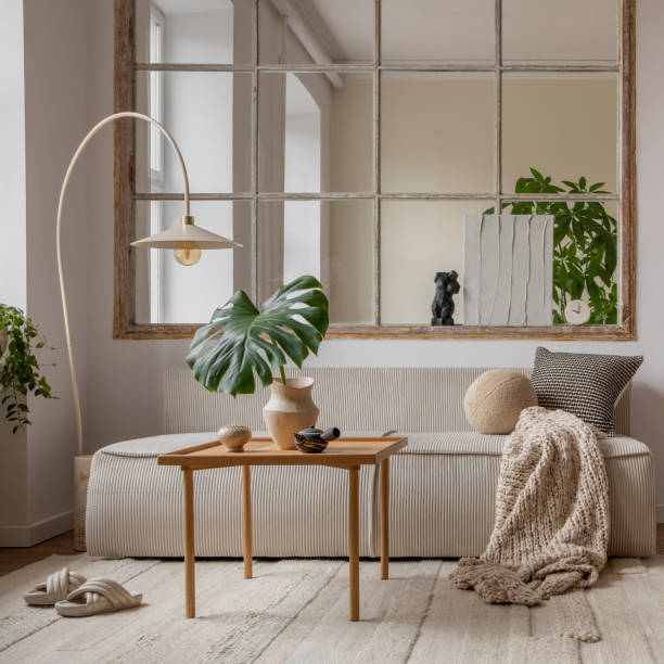 istock Interior design of open space interior with modular sofa, big window, stylish lamp, wooden coffee table, round table, rattan chair, pillows, plants and personal accessories. Home decor. Template. 1495354797