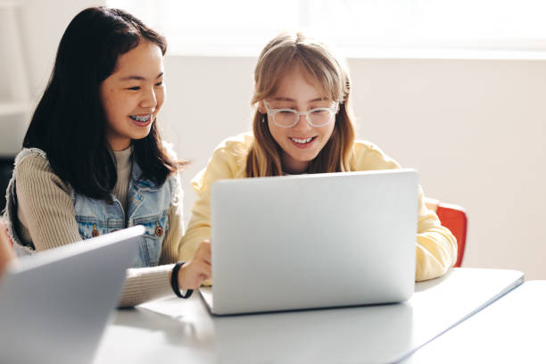 istock Happy female classmates doing a digital literacy task together in a classroom 1495355496