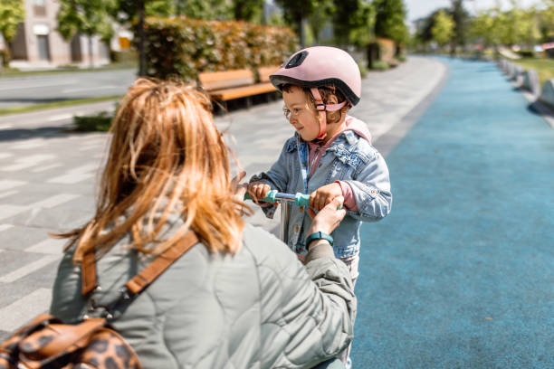 istock Mother and cute little daughter embracing and having fun together while learning how to ride a push scooter 1495355793