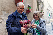 Senior man giving a bouquet of onion to a senior woman in an Italian town
