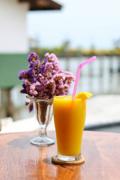 istock Mango smoothie in a tall glass placed on a table by the sea. 1495372280