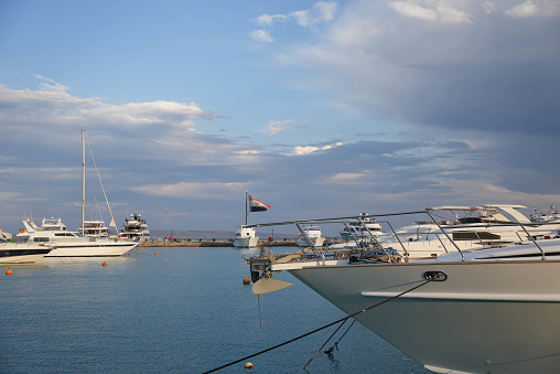 Luxury yachts docked at sea port at sunset. Marine parking of modern luxury boats and blue cloudy sky. Tranquility, calm and affluent vacation. High quality photo