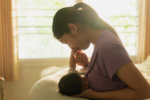 Asian mom is breastfeeding newborn at home