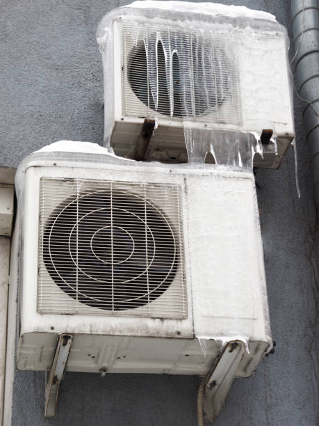 istock Outdoor inverter compressor unit of split-system air conditioner installed outside the building. Equipment in ice in the winter season. High quality photo 1495383425