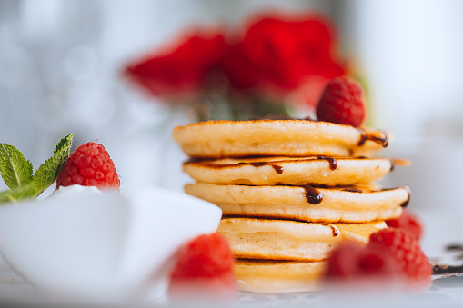 A pile of fresh pancakes with chocolate and fresh raspberries