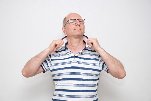 Caucasian man 50 years old on a gray background in a light shirt and glasses, looking at the camera. series of emotions.