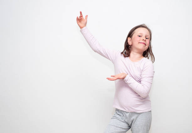 portrait d’une fille de race blanche de 7 à 9 ans sur fond gris, geste indique la direction et sourit regarde dans l’objectif - female 8 9 years child excitement photos et images de collection
