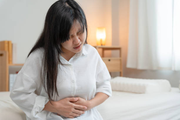 腹痛。アジアの女性は腹痛、消化不良、胃炎、月経痛、鼓腸、下痢、膨満、結腸癌、腹部炎症の問題、食中毒、腹部に苦しんでいます - 月経前症候群 ストックフォトと画像