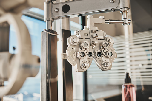 Vision, optometry and healthcare in an optician office with an ophthalmic phoropter machine for testing. Hospital, medical and eye health with test equipment in an empty room at the optometrist