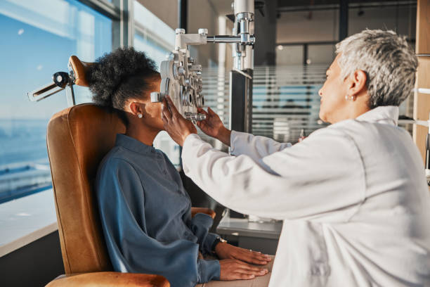 istock Vision test, eye exam and black woman with optometrist for testing, eyesight and optical assessment. Healthcare, optometry office and patient with medical equipment, phoropter and lens for eyes 1495398526