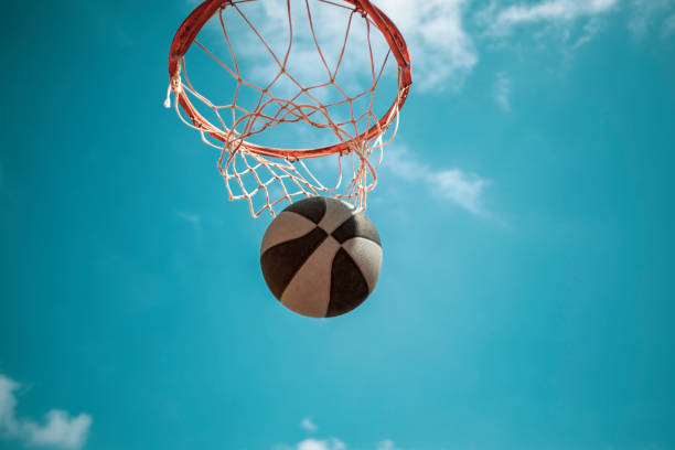 istock Basketball hoop seen from below with the blue sky and a dunking ball 1495398736