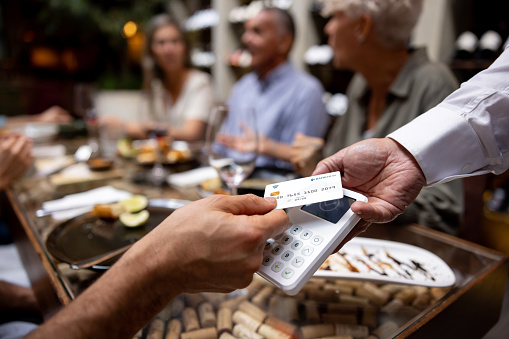 Close-up on a man making a contactless payment at a restaurant using his credit card