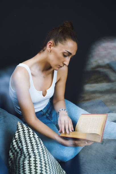 istock Woman reading book at home 1495404296