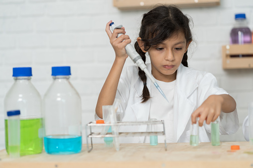 Child girl learning science and analyse liquid in the laboratory at school. Science and education, researcher and discovery concept