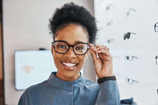 Glasses check, black woman portrait and shoppoing of in a store looking through lense. Eye consulting, smile and eyewear assessment in a frame shop for vision test and prescription exam for eyes