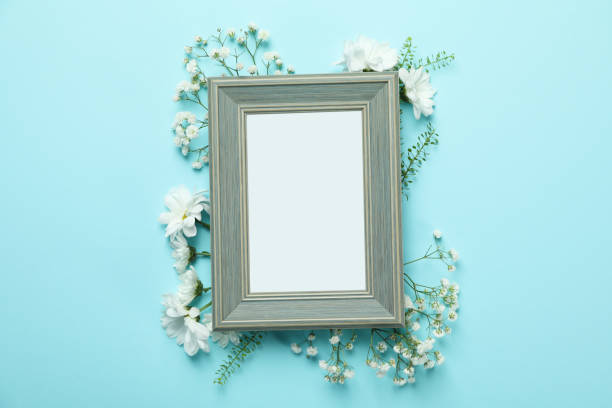 istock Blank photo frame with flowers on blue background 1495408374