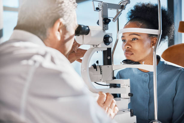 Help, eye exam or black woman consulting doctor for eyesight at optometrist or ophthalmologist. African customer testing vision with mature optician checking iris, glaucoma or retina visual health stock photo