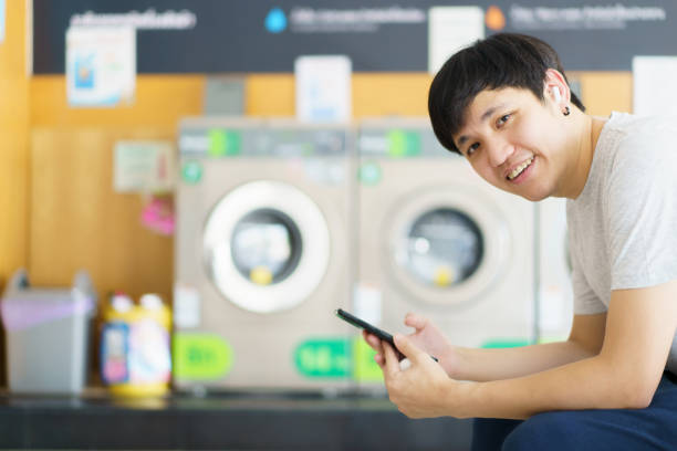 homme lavant des vêtements dans un magasin de machines à laver en libre-service. - all laundry detergent audio photos et images de collection