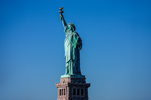 Statue of Liberty in a blue summer sky. Landmark of New York\nBlue sky background with copy space