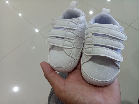 A Photo of a cute little white baby shoe with triple adhesive