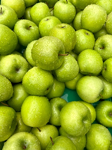 apples, water drops on delicious and beautiful fresh green apples. food background with heap of ripe fruits. healthy food or ripe fruit concept