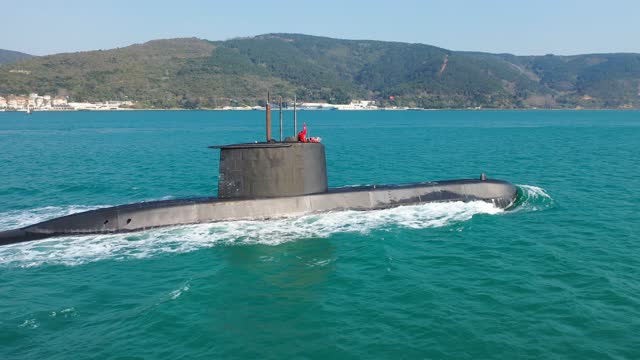 Navy submarine underway on calm waters waving the Turkish flag. Ships of impartial states can pass through Straits as during peacetime while ships of warring states prohibited from passing through