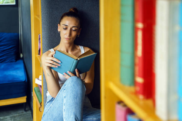 istock Woman reading book at home 1495414532
