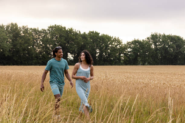 A wide angle view of a couple who are enjoying an early morning stroll around the villa that they are staying at in Toulouse in the South of France. They are walking through wheat fields and appreciating the beautiful French weather