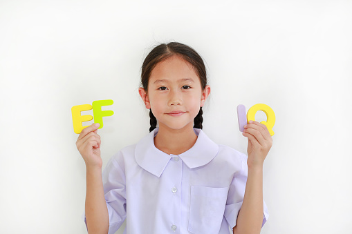 Asian little girl child in school uniform holding alphabet EF and IQ (Executive Functions and Intelligence Quotient) isolated on white background. Education concept