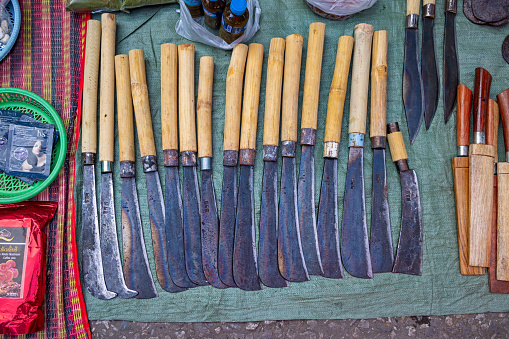 Morning Market, Luang Prabang, Laos - March 21th 2023: Line of hand made knives for sale at the market in the center of the former capital of Laos