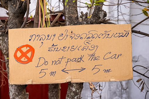 Luang Prabang, Laos - March 16th 2023: Home made sign asking people not to park in front of a building in a suburb to the former capital of Laos