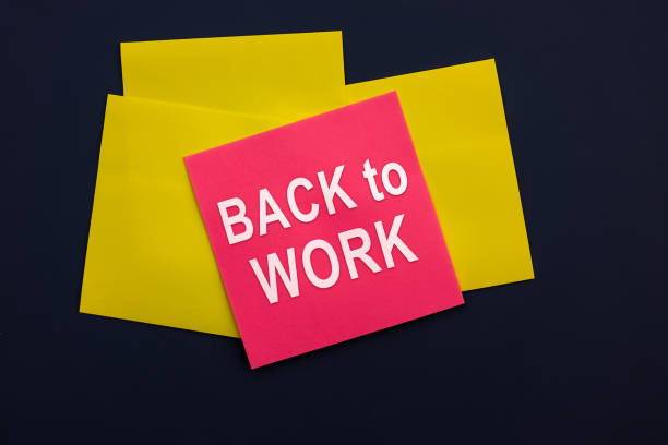 istock Back to work - inscription of a pink square sticky note paper on dark background. Top view. Business and marketing concept 1495417531