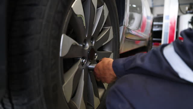 Close up on unrecognizable mechanic removing a flat tire to patch it at an auto repair shop
