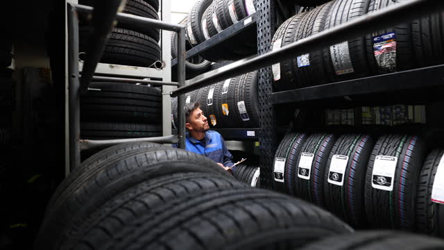 Focused man doing inventory of different tire brands on shelves