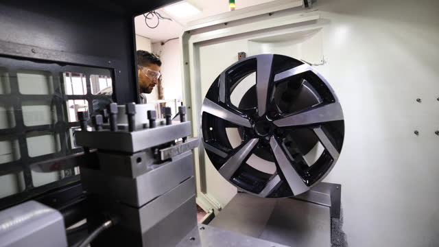 Latin American mechanic testing an alloy wheel at a car garage