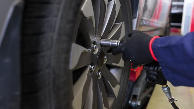 Close-up of a mechanic unscrewing the rim bolts to change a tire at an auto repair shop