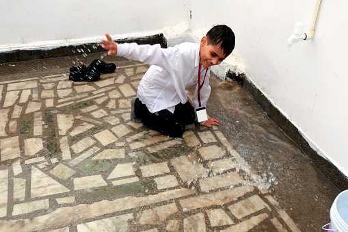 Elementary age school child of Indian ethnicity  playing with water during rainy season.