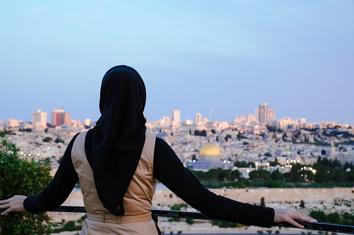asian muslim woman standing at The Old Town with the Dome of the Rock at the sunset from Mount of Olives
