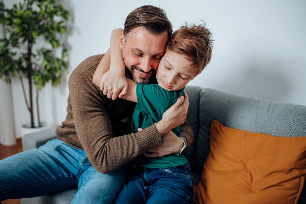 istock Mid Adult Man Holds His Son Close on the Sofa 1495423613