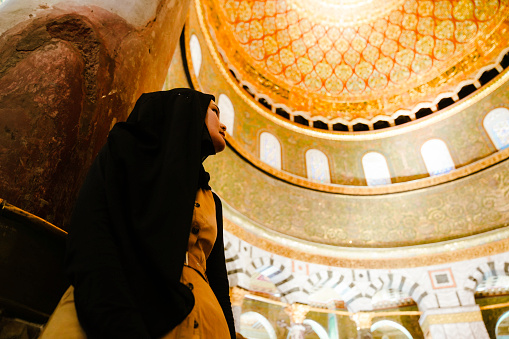 asian muslim woman looking at interior of dome of the rock