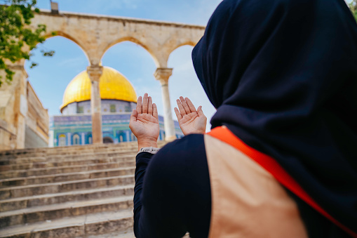 asian muslim woman praying with dome of rock at the background